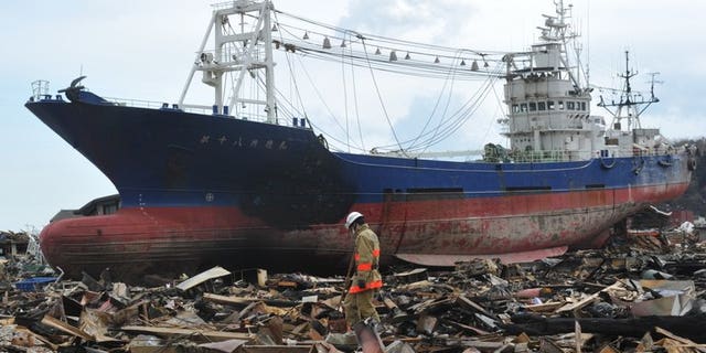 This file photo shows rescuers searching through debris in front of a large grounded ship, in Kesennuma, Miyagi prefecture, on March 17, 2011. The fishing boat that became one of the most poignant symbols of the tsunami disaster is to be scrapped, authorities announced on Tuesday.