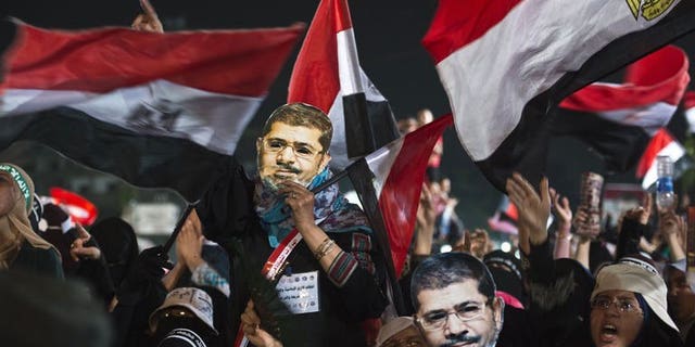 Female members of the Muslim Brotherhood hold up masks of Egypt's ousted president Mohammed Morsi as they take part in a sit-in protest outside the Rabaa al-Adawiya mosque in Cairo, on August 12, 2013. Egyptian police have fired tear gas to break up clashes between supporters of Morsi and residents of a central Cairo neighbourhood, AFP correspondents said.