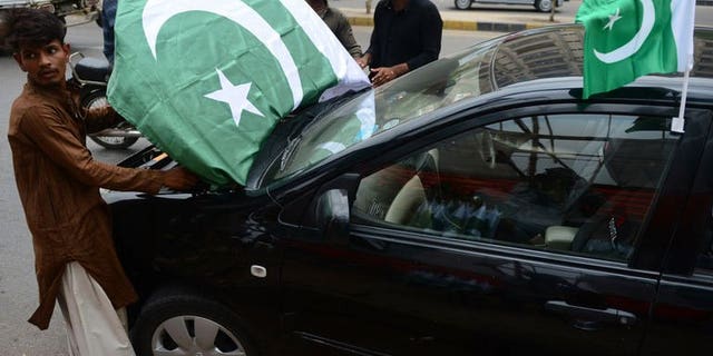 Pakistani vendors decorate a car with national flags ahead of the country's Independence Day in Karachi on August 12, 2013. Twin hand grenade attacks killed at least two people and wounded 28 others belonging to a Shiite Muslim community in Pakistan's port city of Karachi on Tuesday, officials said.