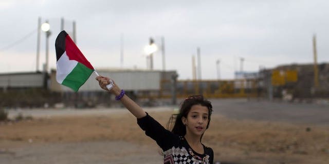 A Palestinian girl from the Israeli occupied West Bank waves the national flag close to the Israeli military prison of Ofer, in the village of Betunia, waiting for the release of Palestinian prisoners on August 13, 2013. An Israeli operation to free 26 Palestinian prisoners got under way late on Tuesday when two busloads of detainees left a jail near Tel Aviv.