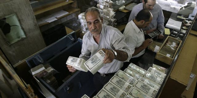 An employee stacks Syrian banknotes at the Syrian Central Bank in Damscus, on August 25, 2011. The central bank in war-torn Syria has lifted restrictions on the sale of dollars to individuals, in a bid to curb black market trade.