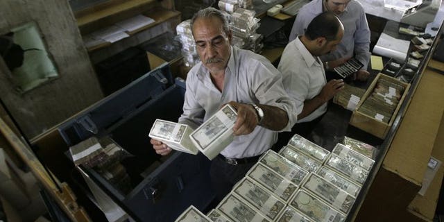 An employee stacks Syrian banknotes at the Syrian Central Bank in Damscus, on August 25, 2011. The central bank in war-torn Syria has lifted restrictions on the sale of dollars to individuals, in a bid to curb black market trade.
