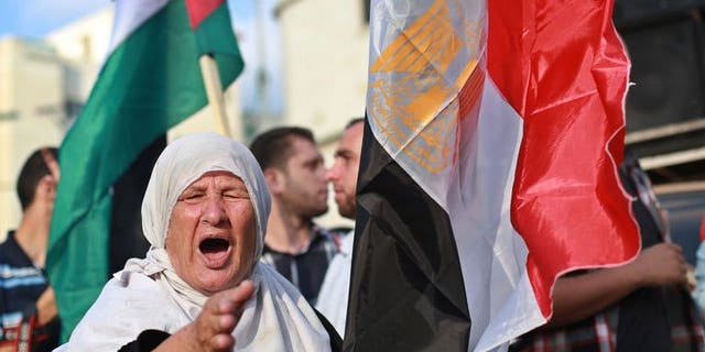 A Palestinian supporter of ousted Egyptian president Mohamed Morsi, shouts slogans as she stands in between the Egyptian (R) and Palestinian flags during a protest against the violence in the Egyptian capital on August 14, 2013, in Gaza City. The Palestinian Islamist movement Hamas condemned Egypt's bloody crackdown on supporters of ousted president Mohammed Morsi as a "terrible massacre."