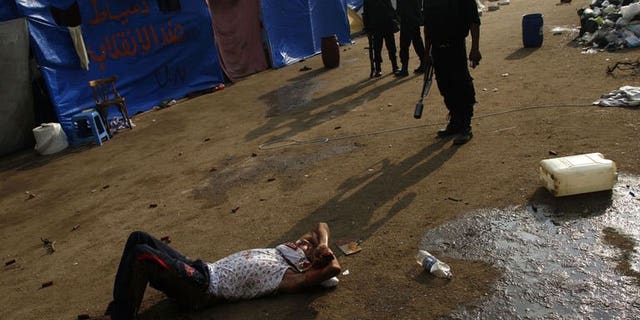 Egyptian riot policemen stand behind a wounded youth during clashes that broke out as Egyptian security forces moved in to disperse supporters of Egypt's deposed president Mohamed Morsi in a huge protest camp near Rabaa al-Adawiya mosque in eastern Cairo on August 14, 2013.