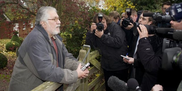 British radio and television presenter Dave Lee Travis (L) speaks to the media outside at his home in Buckinghamshire, England, on November 16, 2012. Travis was charged on Thursday with 11 counts of indecent assault of women and girls as young as 15 and one count of sexual assault, prosecutors said.