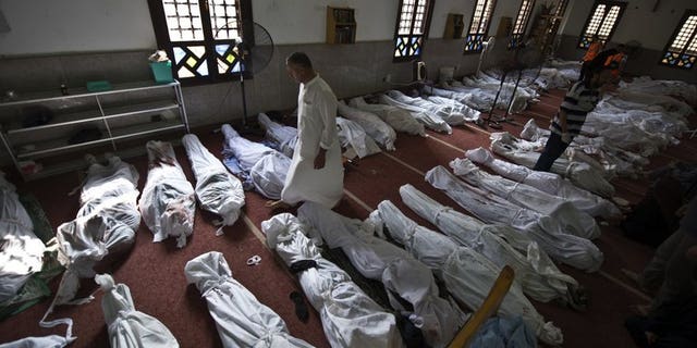 An Egyptian man walks between lines of bodies wrapped in shrouds at a mosque in Cairo on August 15, 2013. Egyptian police on Thursday entered a Cairo mosque containing the bodies of several dozen killed Islamist protesters after a brief standoff during which they fired tear gas, Islamist activists said.