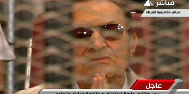 An image grab taken from Egyptian state TV shows ousted Egyptian president Hosni Mubarak gesturing behind bars during a hearing in his retrial at the police academy in Cairo on July 6, 2013. The trial of former Egyptian president Hosni Mubarak on charges of complicity in the deaths of protesters was adjourned on Saturday until August 25, after a brief session.