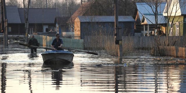 A man rows a boat across a flooded street during spring floodings in the suburb of the town of Bryansk, on April 19, 2013. More than 17,000 people have been evacuated in Russia's flood-hit Far East, a minister said Saturday, warning this figure could reach 100,000 as floodwaters wreak havoc across the region.
