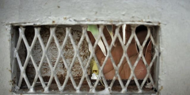 In this photograph taken on February 25, 2012, a prisoner's hands cover the window of an iron door of Kerobokan prison on Bali. About 30 prisoners escaped from an overcrowded jail on Indonesia's Sumatra island on Sunday after riots broke out, officials said.