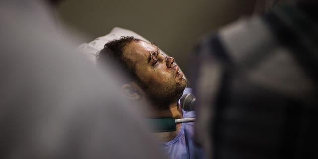 International and local media interview an Egyptian police officer lying on his hospital bed on August 18, 2013 as he recovers from gunshots wounds sustained during clashes with supporters of ousted president Mohammed Morsi, in Cairo. An Islamist alliance opposed to the Egyptian military's ouster of president Mohamed Morsi called off rallies that they planned to stage in Cairo on Sunday.