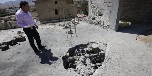 A Lebanese man inspects the damage after a rocket coming from Syria fell on his house in the town of Hermel, a few kilometres from Baalbek in the Bekaa valley, on April 26, 2013. Five rockets landed in and around the eastern Lebanese town of Hermel, a Hezbollah stronghold, on Sunday, a security source told AFP on condition of anonymity.