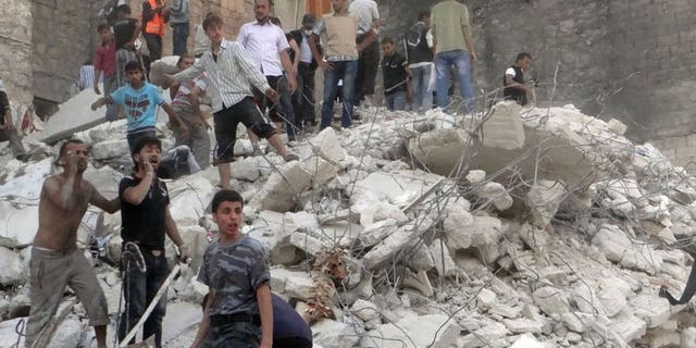 Men stand on debris from a building which collapsed after it was allegedly bombed on August 16, 2013 in Aleppo. Syria's President Bashar al-Assad said on Sunday he is determined to "eradicate terrorism" which he blames for the conflict raging in his country, according to state news agency SANA.