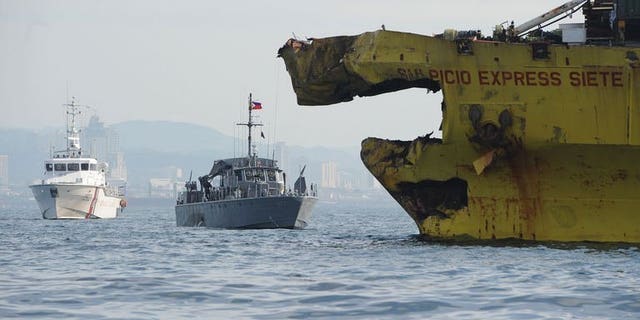A Philippine Coast Guard ship (L) and navy patrol boat (C) anchored next to a damaged cargo ship on August 17, 2013 after it collided with the ferry St. Thomas Aquinas near the central city of Cebu. The confirmed death toll from the ferry disaster rose to 64 on Tuesday as more bodies were found, some of them inside the sunken ship itself.
