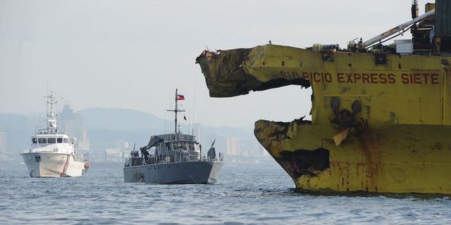 A Philippine Coast Guard ship (L) and navy patrol boat (C) anchored next to a damaged cargo ship on August 17, 2013 after it collided with the ferry St. Thomas Aquinas near the central city of Cebu. The confirmed death toll from the ferry disaster rose to 64 on Tuesday as more bodies were found, some of them inside the sunken ship itself.