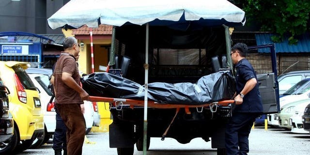 Picture taken on July 29, 2013 shows Malaysian forensic police carrying the body of late Arab Malaysian Banking Group founder Hussain Ahmad Najadi after he was shot dead on a street in Kuala Lumpur. Malaysian police said they killed five suspected gang members in a shootout early Monday and arrested 200 people in a crackdown on a spate of violent crime that has shocked the country.