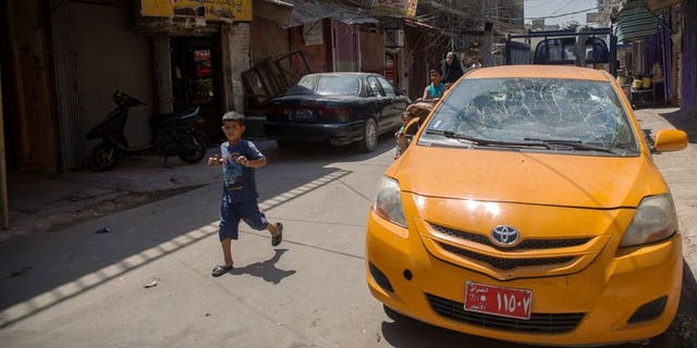 A boy runs past a taxi which was damaged by a bombing in the Allawi neighbourhood of central Baghdad on August 15, 2013. Attacks on Monday killed six people in Iraq, as gunmen defied massive government operations to stem some of the worst violence to have hit the country in five years.