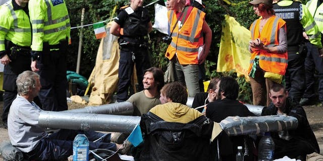 Anti-fracking and climate protesters with their arms bound together demonstrate near the test drill site operated by British energy firm Cuadrilla Resources in Balcombe, southern England, on August 19, 2013.
