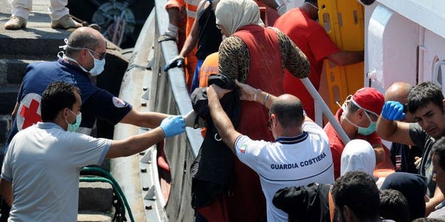 Coast guard help immigrants on August 19, 2013 in the Catania harbor after being rescued off the Italian coast. Four boats carrying more than 350 migrants including Egyptians and Syrians have landed in Italy, officials said Monday, the latest arrivals due to the growing unrest in north Africa.