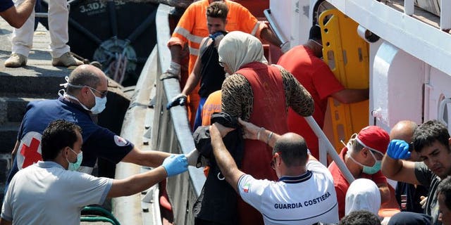 Coast guard help immigrants on August 19, 2013 in the Catania harbor after being rescued off the Italian coast. Four boats carrying more than 350 migrants including Egyptians and Syrians have landed in Italy, officials said Monday, the latest arrivals due to the growing unrest in north Africa.