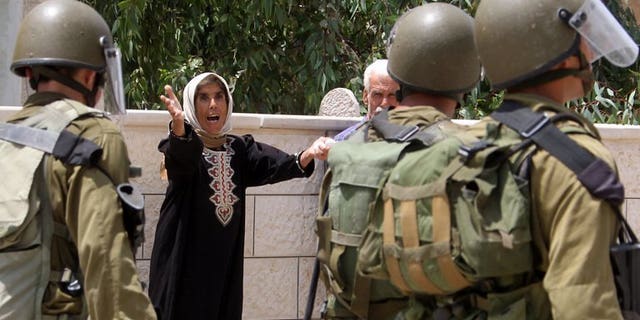 A Palestinian woman yells at Israeli soldiers during clashes following a protest in the village of Kfar Qaddum, near Nablus in the occupied West Bank on July 19, 2013. Israeli troops shot dead a Palestinian and wounded two others during an operation early Tuesday to arrest a Palestinian militant in the West Bank city of Jenin, the army said.