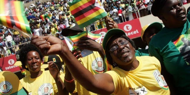 Supporters of Zimbabwe's President Robert Mugabe wave flags upon his arrival at the commemoration of Defence Forces Day in Harare on August 13, 2013. Zimbabwe's constitutional court on Tuesday ruled that a disputed elections which handed Robert Mugabe five more years in power were free and fair, dismissing allegations of vote-rigging.