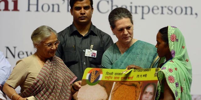 India's ruling Congress party chief Sonia Gandhi (2L) presents a woman with an ceremonial food card as Delhi Chief Minister Sheila Dixit (L) looks on during the launch of the Food Security Programme in New Delhi, August 20, 2013. Gandhi on Tuesday launched the landmark public food scheme for hundreds of millions of people, declaring it would banish hunger and be free of corruption.