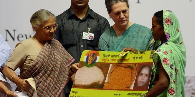 India's ruling Congress party chief Sonia Gandhi (2L) presents a woman with an ceremonial food card as Delhi Chief Minister Sheila Dixit (L) looks on during the launch of the Food Security Programme in New Delhi, August 20, 2013. Gandhi on Tuesday launched the landmark public food scheme for hundreds of millions of people, declaring it would banish hunger and be free of corruption.