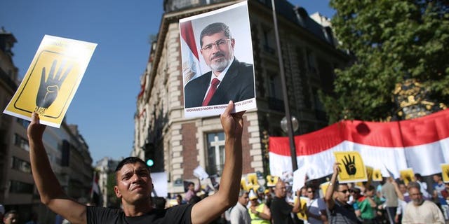 A protester holds a placard reading "R4BIA" (L) and a poster of Egypt's ousted president Mohamed Morsi during a protest against army-installed Egyptian government, in front of the Saudi Arabia's embassy in Paris, on August 20, 2013. Europe stood poised to firmly condemn the blistering violence in Egypt but stop short of sanctions as EU foreign ministers gathered Wednesday.