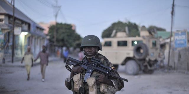 An AMISOM soldier monitors a street in Mogadishu. Gunmen killed two Somalis and wounded a Swedish woman in central Mogadishu on Wednesday when they opened fire on their car in the latest attack in the troubled city, police said.
