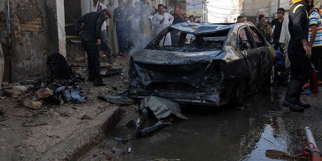 Iraqis gather near the remains of a vehicle at the scene of a car bomb in Nasiriyah, south of Baghdad on August 19, 2013. Attacks in Iraq killed seven people, damaged an oil pipeline and hit a Shiite shrine on Wednesday, as the country grapples with a months-long spike in violence.