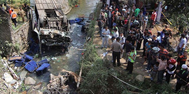 Indonesian police and officials examine the scene of an accident after a bus (L) plunged into a river in Cisarua, Bogor, in West Java on August 21, 2013. Eighteen people were killed and dozens injured Wednesday when a bus plunged into a river as it returned from a church outing on Indonesia's main island of Java, police said.