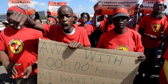 Workers on strike hold signs as they take part in a demonstration outside Ford's plant in Pretoria on August 20, 2013. A striking South African auto workers union will meet manufacturers on Thursday in a bid to break a wage deadlock that has crippled a multi-billion dollar export market.