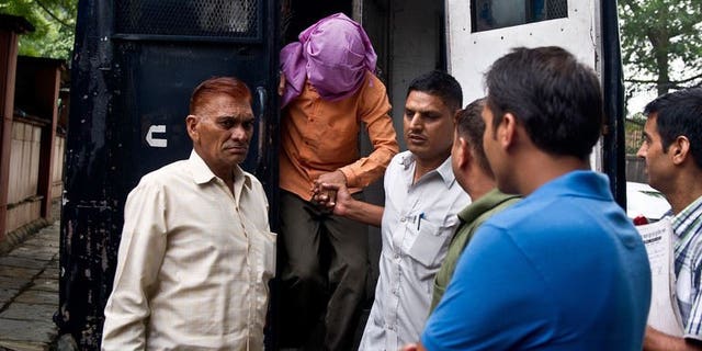 Indian policemen escort the juvenile accused (2nd L) in the December 2012 gang-rape of a student, from a police vehicle outside the juvenile court in New Delhi on August 19, 2013. The trials of five suspects for the fatal gang-rape of an Indian student on a bus last December moved towards their conclusions on Thursday, with the first verdict set for August 31.