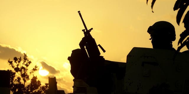 A Member of United Nations Interim Force in Lebanon (UNIFIL) stands guard next to the reported location of the launch of four rockets at Israel, on the outskirts of the southern Lebanese port city of Tyre on August 22, 2013. The Israeli air force carried out an attack in Lebanon on Friday, the army said, hours after militants there fired four rockets at the Jewish state.
