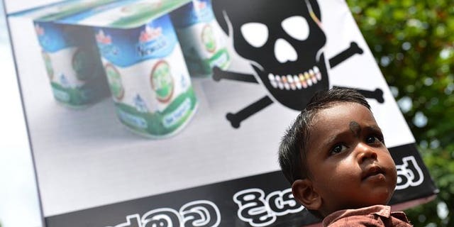 A Sri Lankan child looks on as pro-government activists protest the alleged contamination of milk powder outside the factory of dairy giant Fonterra in a Colombo suburb on August 22, 2013.