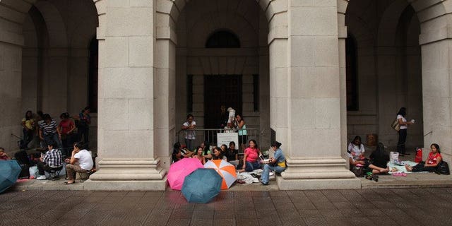 Foreign domestic helpers sit beneath the arches of the former Legislative Council building in Hong Kong on October 2, 2011. A Hong Kong couple left their Indonesian domestic helper without food or water after tying her to a chair and forcing her to wear a diaper while they went on five-day vacation, a report said Saturday.