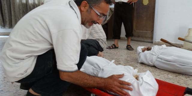 An image released by the Syrian opposition's Shaam News Network on August 23, 2013, shows a relative weeping over the body of an infant killed in an alleged toxic gas attack. Three Syrian hospitals have received around 3,600 patients displaying "neurotoxic symptoms", 355 of whom have died, Doctors without Borders (MSF) say.
