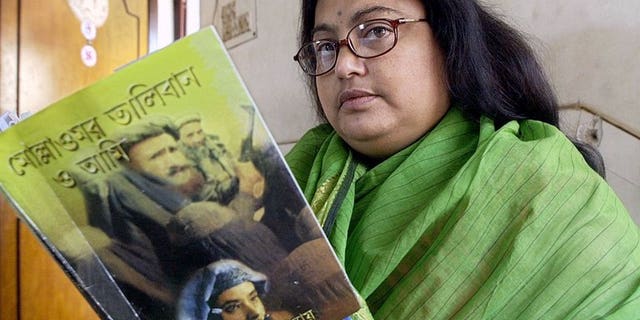 In this photograph taken on March 6, 2003, Indian author Sushmita Banerjee holds one of her Bengali language novels "Mollah Omar Taliban O Aami" (Mollah Omar, Taliban and Me) in Kolkata. Suspected Taliban militants have shot dead Banerjee in the eastern Afghan province of Paktika, police said.