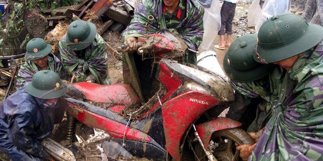 This photo, taken by the Vietnam News Agency on September 5, 2013, shows soldiers pulling out a motorcycle from debris at the scene of flash floods in Sapa district, northern province of Lao Cai. At least 21 people have been killed as flash floods and landslides ravaged mountainous areas in northern Vietnam.