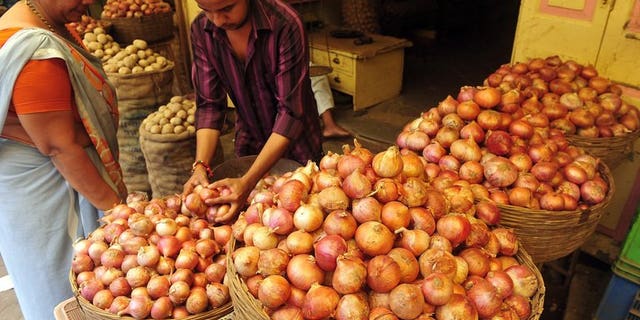 A customer looks on as a shop assistant selects onions for her at a market in Mumbai on August 22, 2013. A US-based website offering onions at heavily discounted prices in India has seen an "overwhelming" response as consumers there reel from sky-rocketing prices of the vegetable.