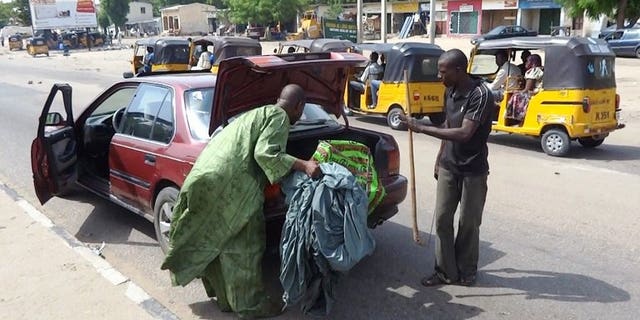 A vigilante peers into the trunk of a car looking for weapons on July 19, 2013 in Maiduguri, where Boko Haram has carried out most of its deadly attacks.
