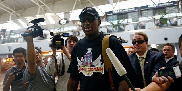 Former US NBA basketball player Dennis Rodman (C) is surrounded by members of the media as he makes his way through Beijing's international airport on September 3, 2013.