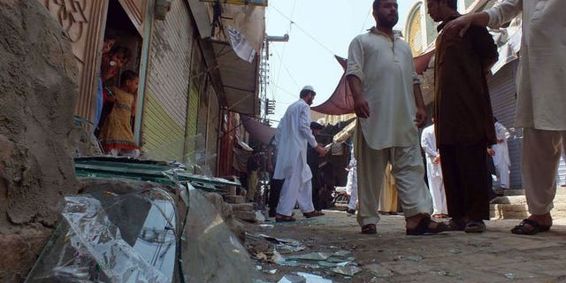 Local residents gather near the site of a bomb explosion in the northwestern town of Bannu on September 5, 2013. Gunmen attacked a mini-bus and two other vehicles near Pakistan's northwestern city of Peshawar late on Friday, killing nine people, police said.