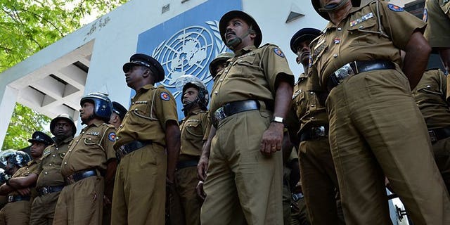 Sri Lankan police stand guard outside the UN office in Colombo on August 31, 2013. Sri Lankan police have arrested a navy officer suspected of involvement in smuggling people in fishing boats to Australia, officials said Saturday.