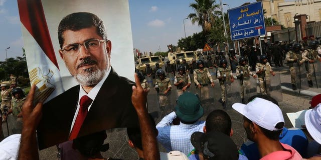 A supporter of ousted Egyptian president Mohamed Morsi holds a picture of the toppled leader in Cairo, on July 19, 2013. An Egyptian prosecutor has levelled new accusations against Mohamed Morsi, already facing trial on other charges, alleging the Islamist had insulted the country's judiciary when he was president, media reported.