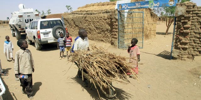 A child pushing a wheelbarrow walks past the entrance to a school in the North Darfur state capital of el-Fasher, on June 17, 2013. Two Red Cross drivers held for almost two weeks in Sudan's troubled Darfur region have been safely released, their organisation said.