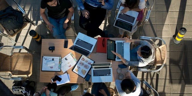 People sit around laptop computers at a cafe in Beijing on May 29, 2013. Chinese Internet users could face three years in prison for writing defamatory messages that are then re-posted 500 times under regulations announced amid a broader crackdown on "online rumours".