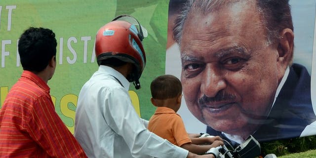 Commuters pictured in front of a roadside banner welcoming and congratulating incoming Pakistani President Mamnoon Hussain in Islamabad on September 9, 2013. He took office on Monday, presiding over a government battling to overcome a Taliban insurgency, resolve an energy crisis and repair the economy.