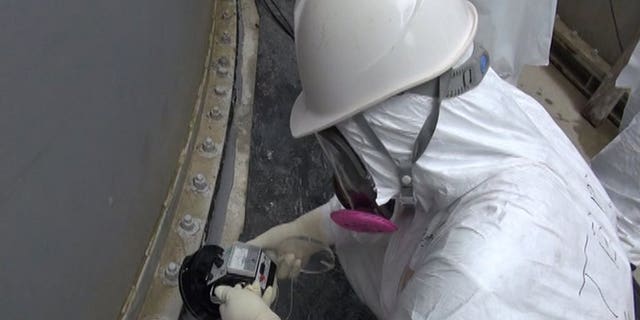 This handout picture taken by Tokyo Electric Power Co (TEPCO) on September 4, 2013 shows a TEPCO worker checking radiation around the contamination water tank at TEPCO's Fukushima Dai-ichi nuclear power plant at Okuma town in Fukushima prefecture.