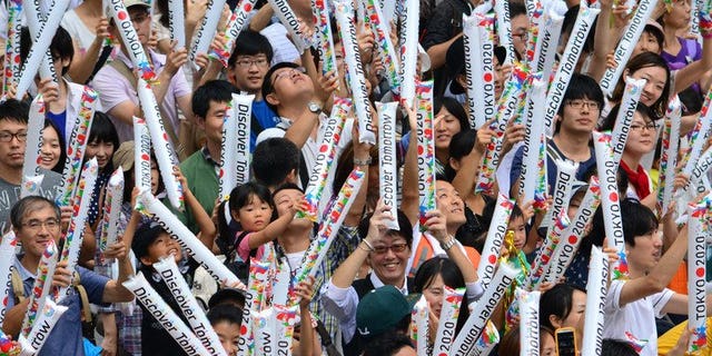 People gathering at the Tokyo metropolitan government building celebrate Tokyo's winning bid to be the host city of the 2020 Olympics on September 8, 2013. Chinese state-run media offered Tokyo heavily qualified congratulations Monday for winning the right to host the 2020 Olympics, saying the event's success would depend on Japan recognising its World War II aggression.